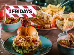 Delicious spread of TGI Fridays food featuring a gourmet burger, crispy fries, shrimp cocktail, and savory dishes on a wooden table, ideal for casual dining and gatherings.