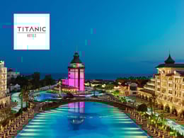 Aerial view of Titanic Hotel with illuminated pools and vibrant architecture at dusk, showcasing a luxurious resort atmosphere.