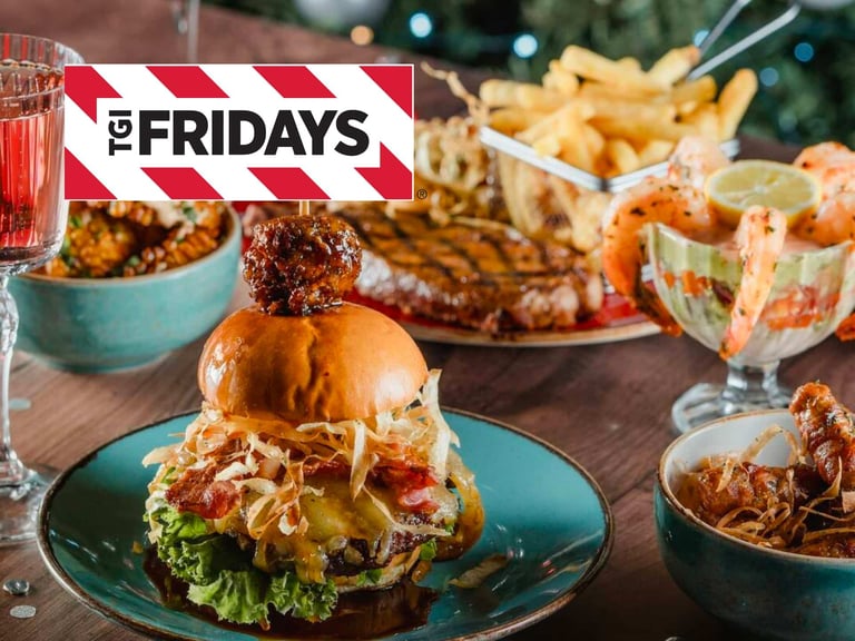 Delicious Spread Of Tgi Fridays Food Featuring A Gourmet Burger, Crispy Fries, Shrimp Cocktail, And Savory Dishes On A Wooden Table, Ideal For Casual Dining And Gatherings.