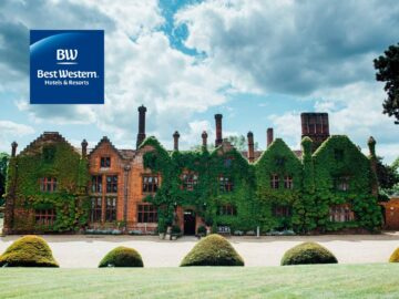 Historic mansion covered in greenery with a scenic landscape, featuring a blue logo in the corner. Ideal for showcasing heritage architecture and natural beauty.