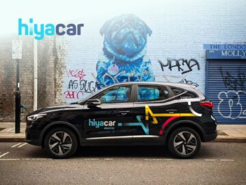 Side view of a Hiyacar branded vehicle parked in front of a colorful mural featuring a dog, showcasing urban art and car-sharing services.