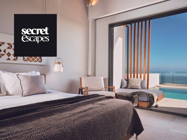 Luxurious Hotel Room With Modern Decor, Featuring A Comfortable Bed And Large Windows Showcasing A Stunning Ocean View. Perfect For A Relaxing Getaway. Secret Escapes Logo In The Corner.
