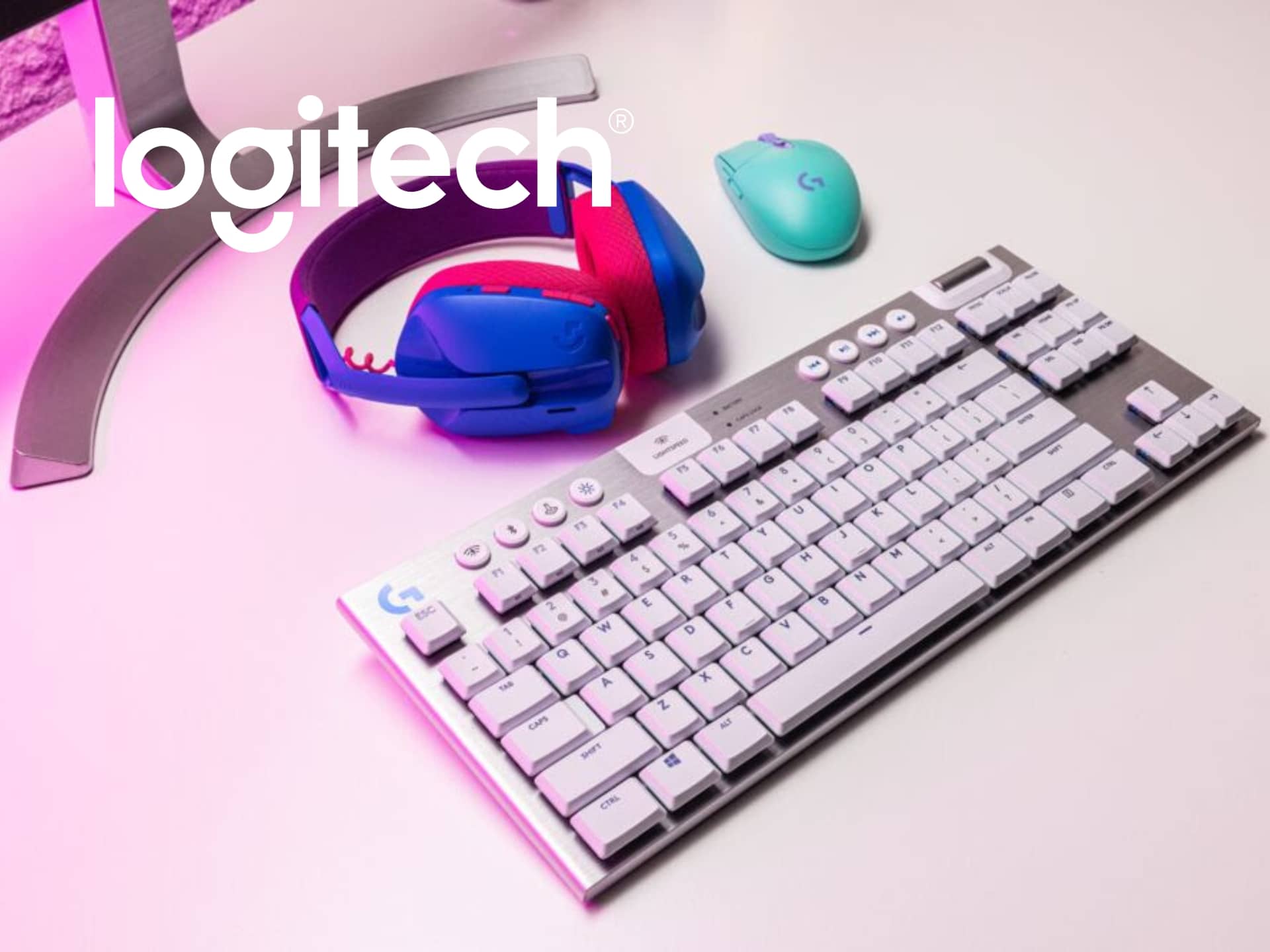 Logitech gaming setup featuring a white mechanical keyboard, colorful gaming headset, and a turquoise wireless mouse, all set against a vibrant background.